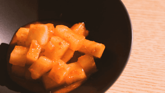 Cubed radish kimchi in a black bowl
