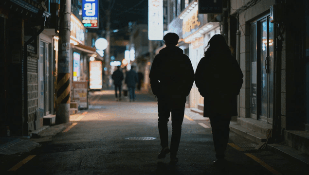 밤에 불빛이 밝은 갈거리에서 걷는 사람들의 뒷모습