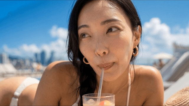 Woman drinking cool beverage by swimming pool