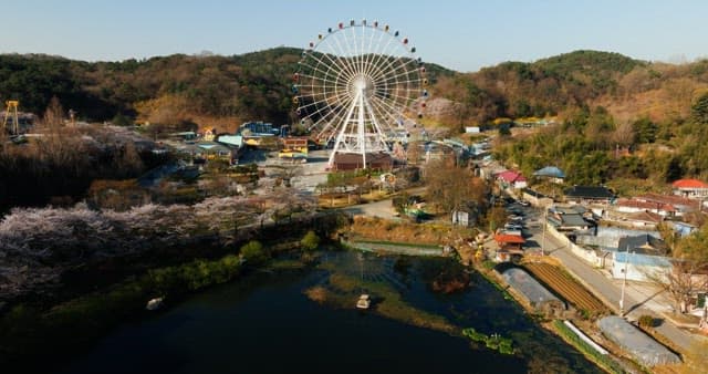 Ferris wheel in a scenic park surrounded by hills