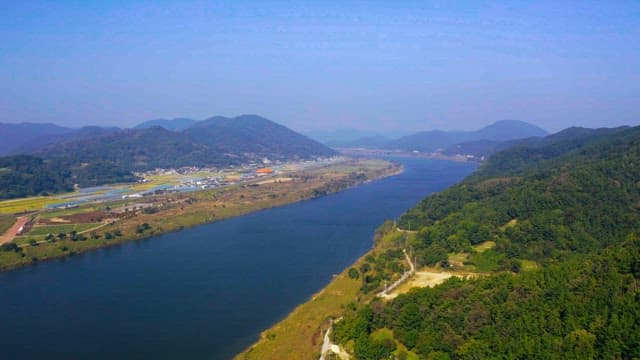 View of a river winding through lush green mountains on a bright sunny day