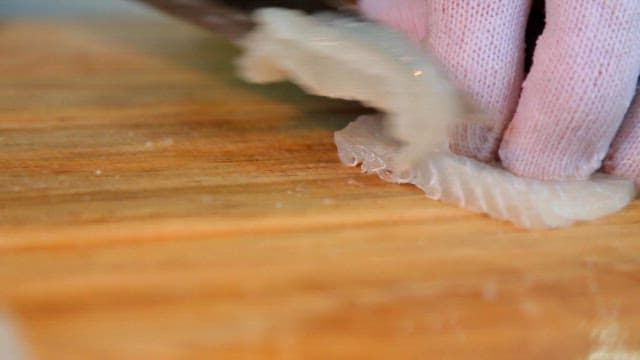 Slicing fresh raw fish on a wooden cutting board