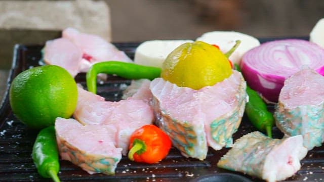 Fresh parrotfish and colorful vegetables grilled on an outdoor barbecue grill