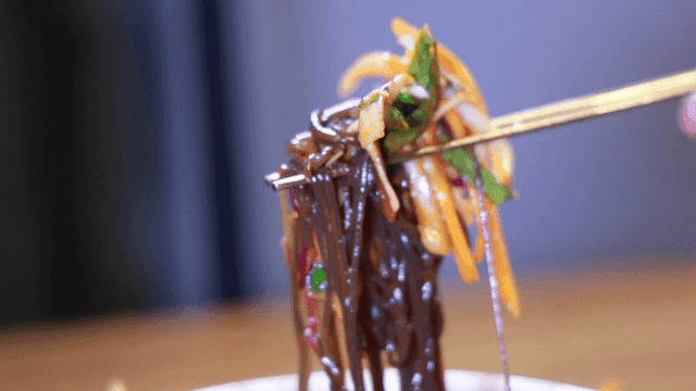 Chopsticks scooping up buckwheat noodles with vegetables