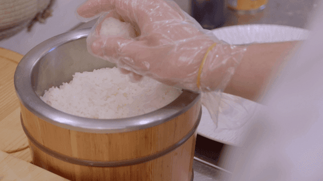 Chef shaping sushi in wooden rice cooker