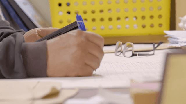 핸드폰을 보며 종이에 메모를 하는 사람