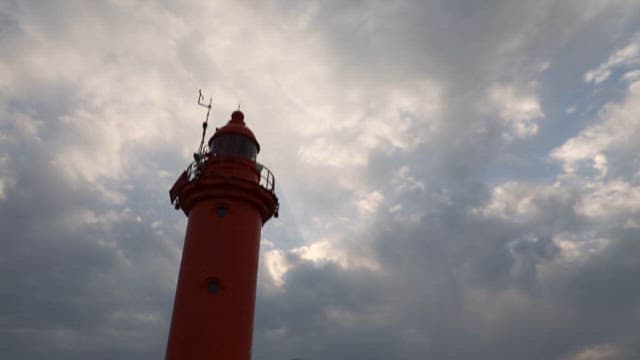 Red Lighthouse Against Cloudy Sky