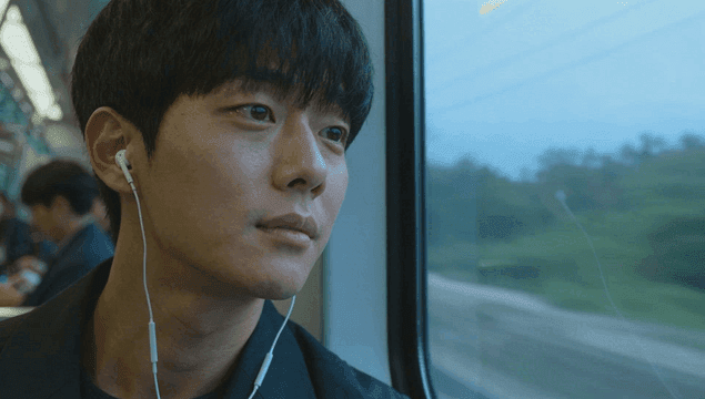 전철에서 음악을 들으며 창밖을 바라보는 젊은 남성