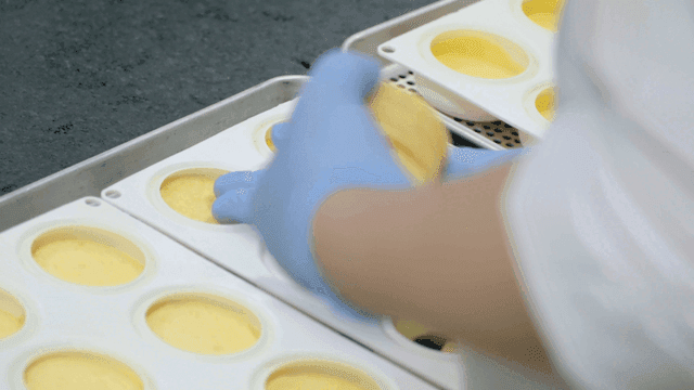 Gloved hands preparing dessert in molds
