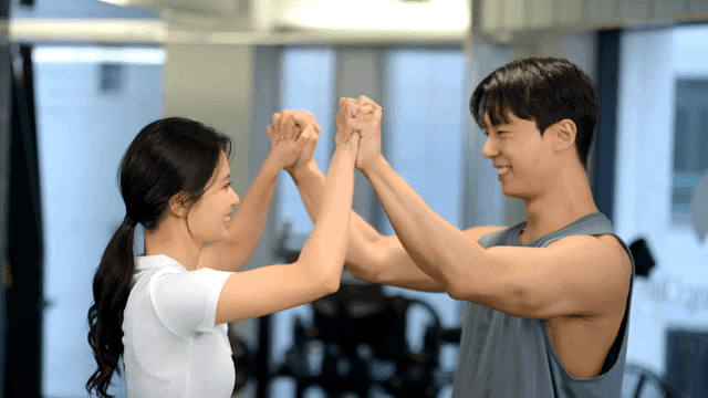 헬스장에서 웃으며 손을 잡고 서로 응원하는 커플