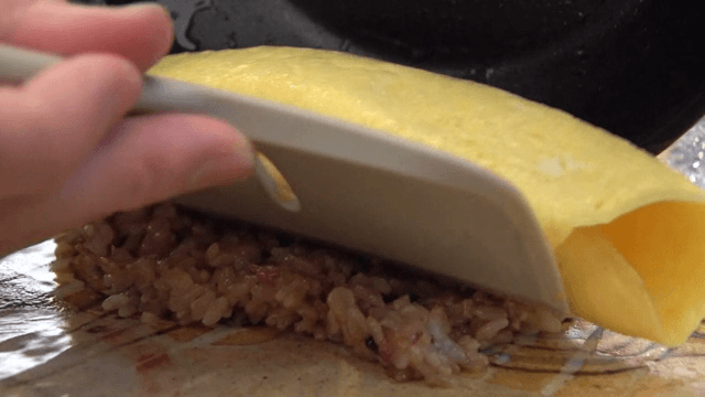 Omelette rice being prepared on a plate