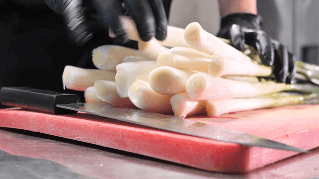 Chef placing green onions on cutting board