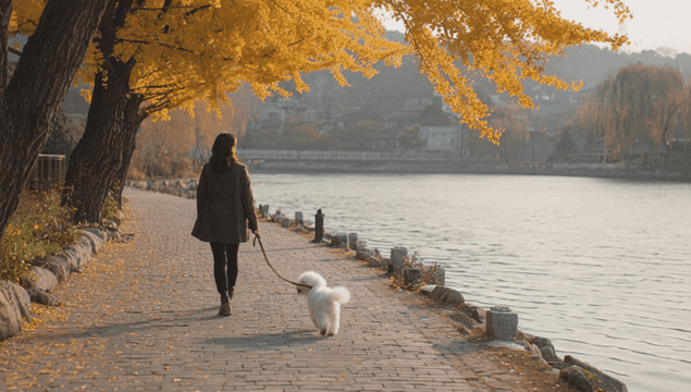 A woman walking a puppy along a lakeside path
