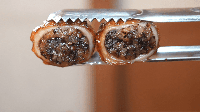 Grilled makchang sundae held with tongs