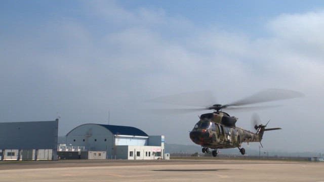 Military helicopter landing on a runway on sunny day