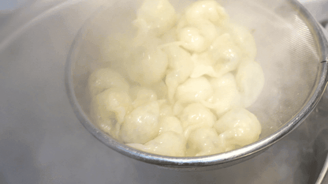 Dumplings scooped out of steaming pot