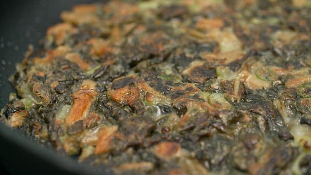 Savory dried radish greens pancake frying in a pan