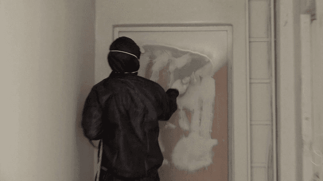 스프레이 건으로 문에 페인트를 칠하는 작업자