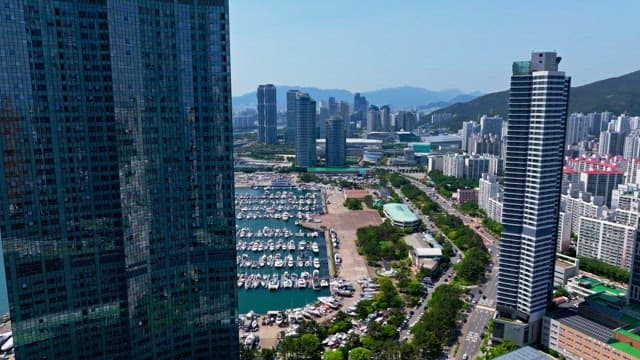 Peaceful coastal town marina with yachts anchored between high-rise buildings on a sunny day