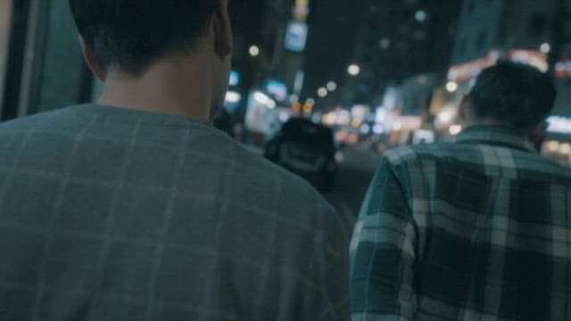 Two Men Walking on a Street of Bustling City at Night