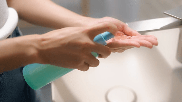 Woman applying cleansing oil to her hands in bathroom