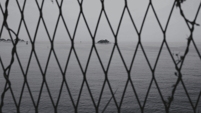 철망 너머로 흐린 날씨에 보이는 바다