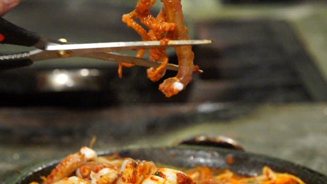 Cutting spicy seasoned braised octopus with scissors