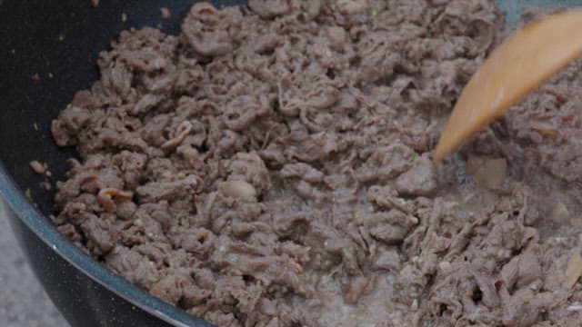 Cooking beef bulgogi with a spatula in a frying pan