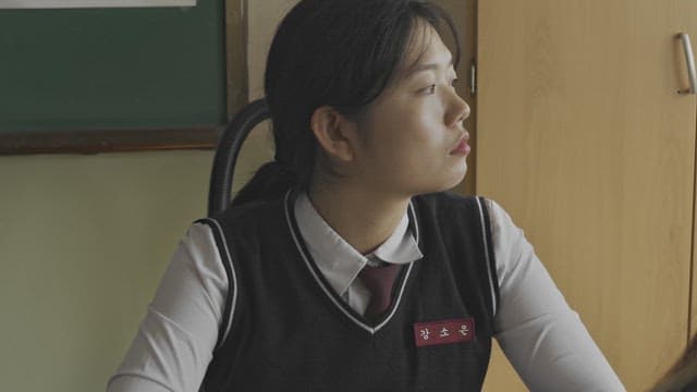 Young student in school uniform looking pensive in a classroom