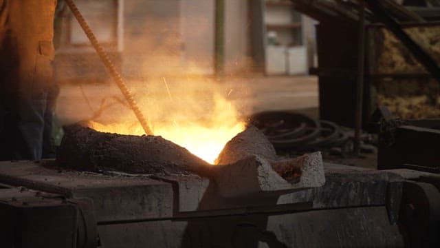 Worker stoking a furnace in a dimly lit workshop