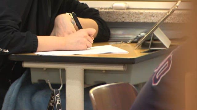 교실에서 문제집과 태블릿을 사용하며 학습하는 학생들