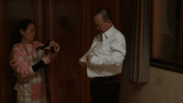 Husband changing clothes after work and wife helping him