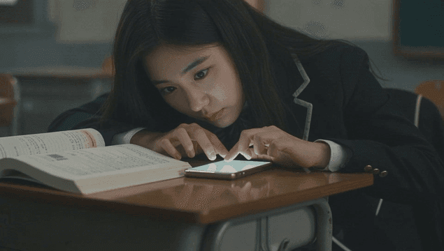 어두운 교실에서 홀로 스마트폰을 사용하는 여학생