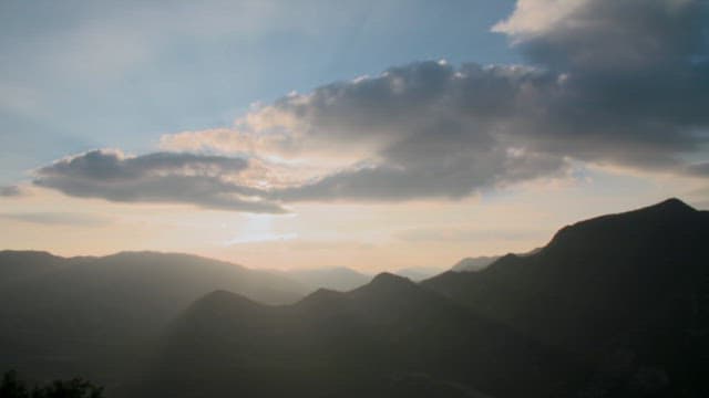 산 위 구름이 흘러가는 하늘을 물들인 석양