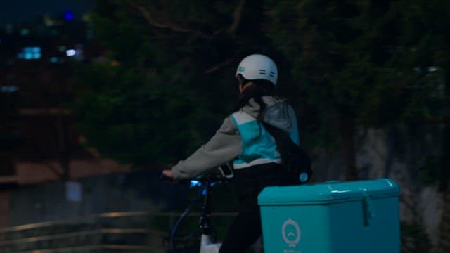 도시의 밤 거리를 이동하는 배달원