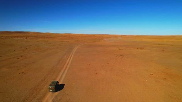 Vehicles Driving Through a Barren and Vast Desert lLandscape