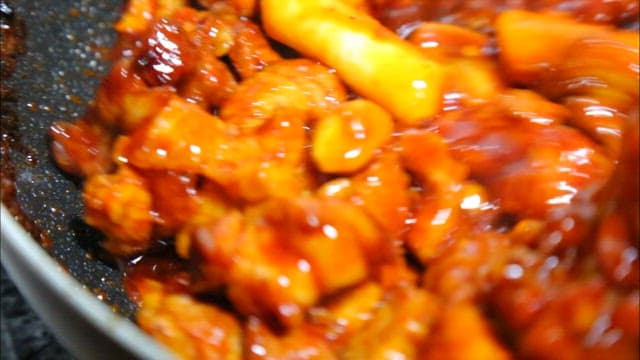 프라이팬에서 요리되는 떡이 들어간 매운 돼지갈비찜