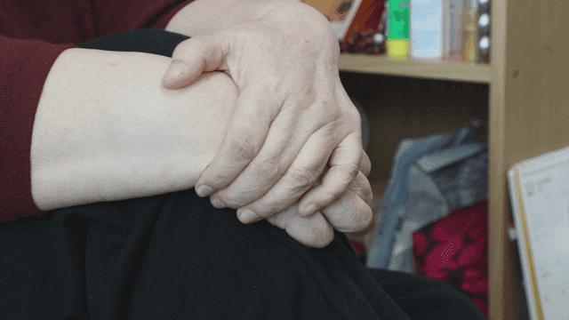 Elderly hands resting on a knee indoors