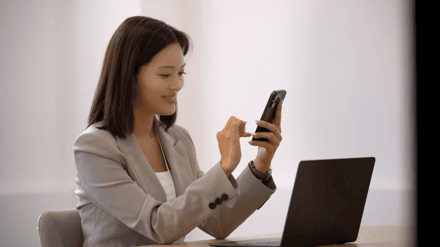 Female office worker using smartphone at her desk