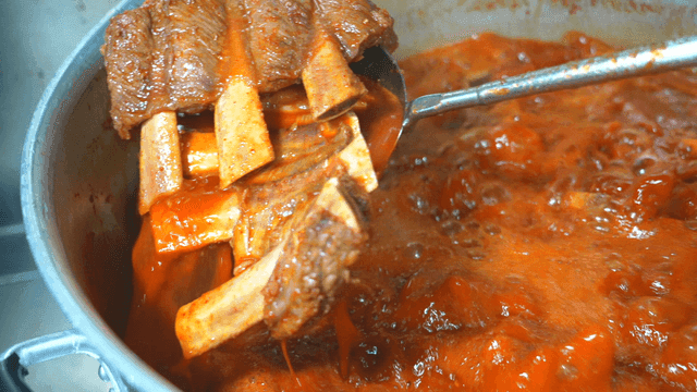 Ladle to scoop out spicy braised short ribs boiling in pot