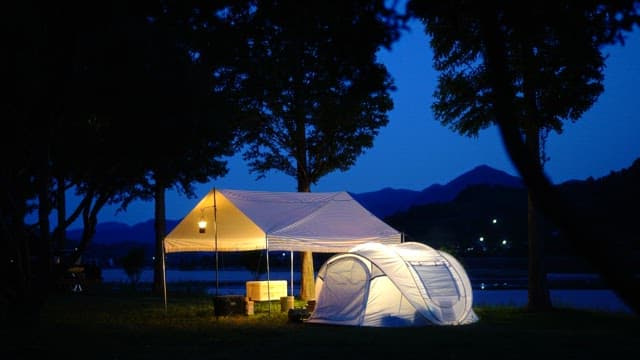 부드러운 조명이 비추는 강가의 저녁 캠핑장