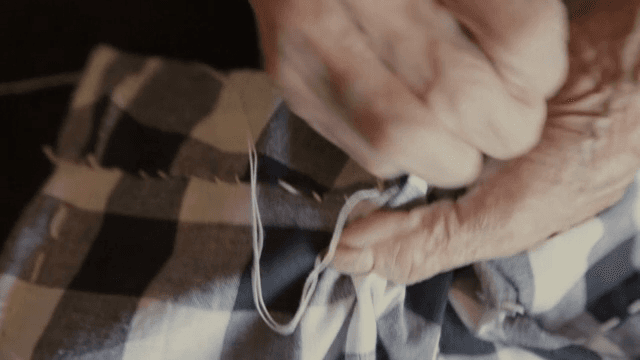 정성스럽게 천을 바느질하는 노인의 손
