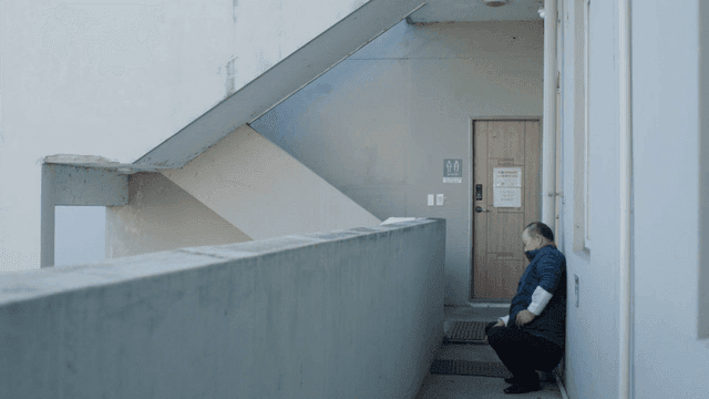 Man sitting in a corridor on a phone call