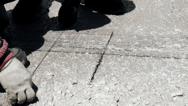 Workers marking lines on concrete surface