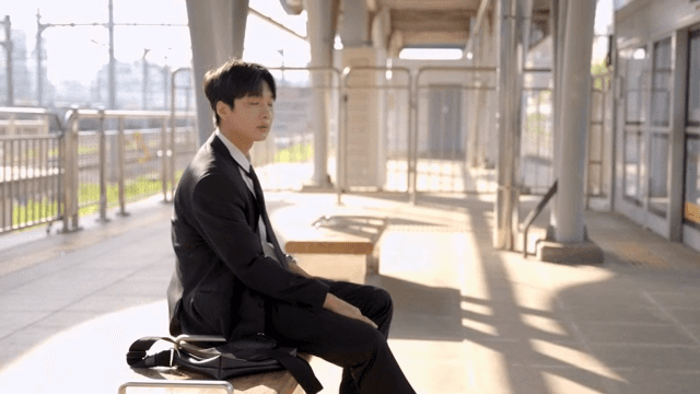 역 의자에 앉아 지하철을 기다리는 직장인 남성