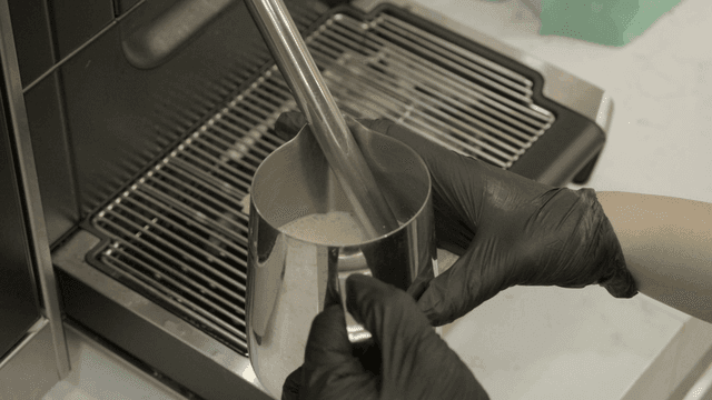 Steaming milk with a frother in a cafe