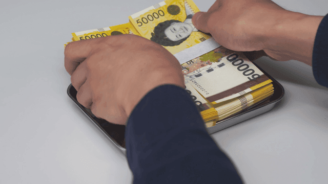 Stack of Korean banknotes being placed on a tray