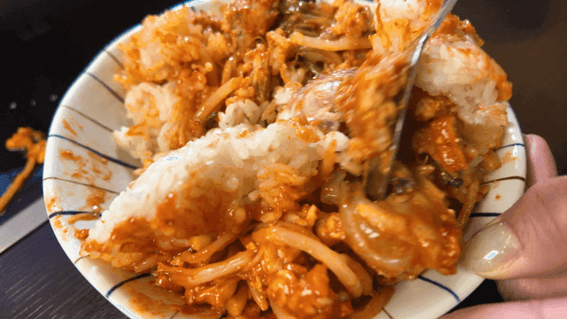 Spoon mixing spicy braised anglerfish into rice