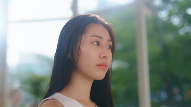 햇빛이 비치는 실내에서 헤어 드라이어로 머리를 말리는 여성