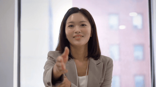 Female office worker smiling and extending handshake in office